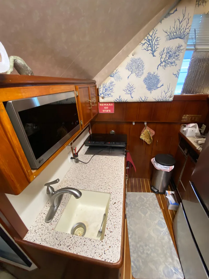 Slide: The Image of 1988 Ocean Yachts 55 Super Sport kitchen with sink, microwave, and nautical decor. - 13