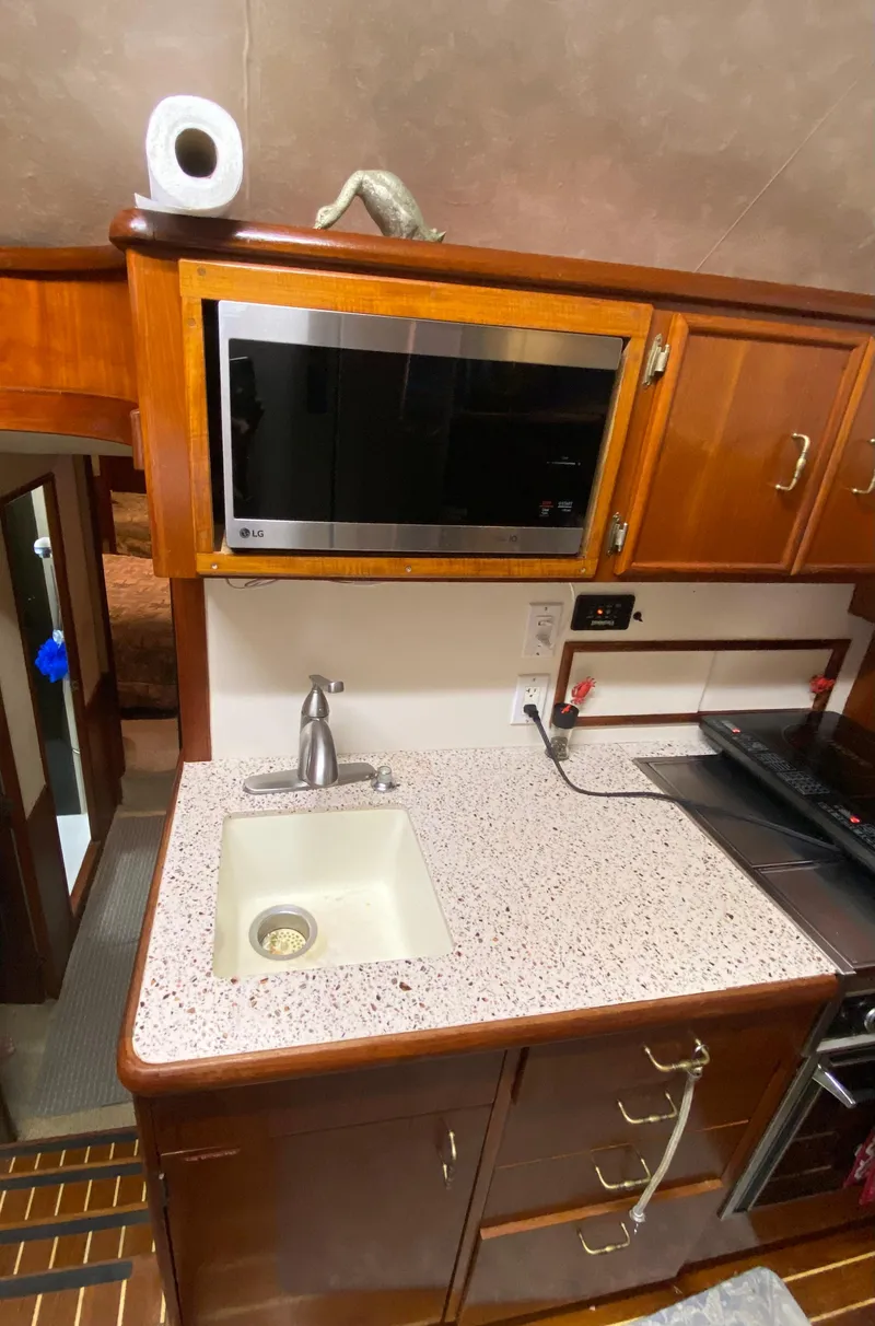 Slide: The Image of 1988 Ocean Yachts 55 Super Sport kitchen with sink, microwave, and wooden cabinetry. - 19