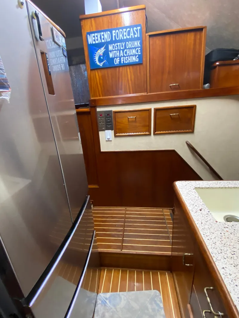 Slide: The Image of 1988 Ocean Yachts 55 Super Sport kitchen with wood cabinetry and humorous fishing sign. - 20