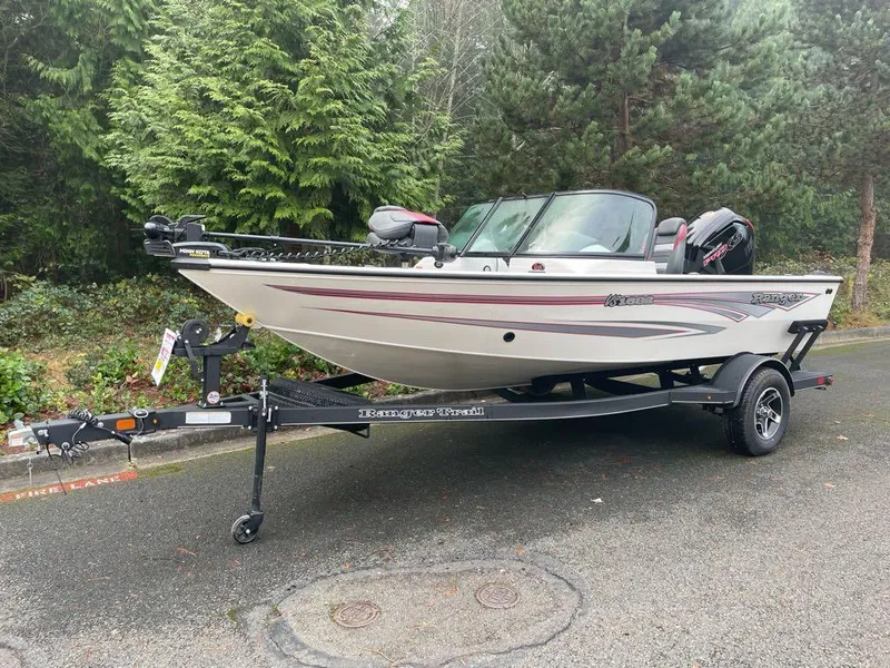 The Image of 2024 Ranger VS1682SC Angler boat on trailer, parked on a forested road. - 0
