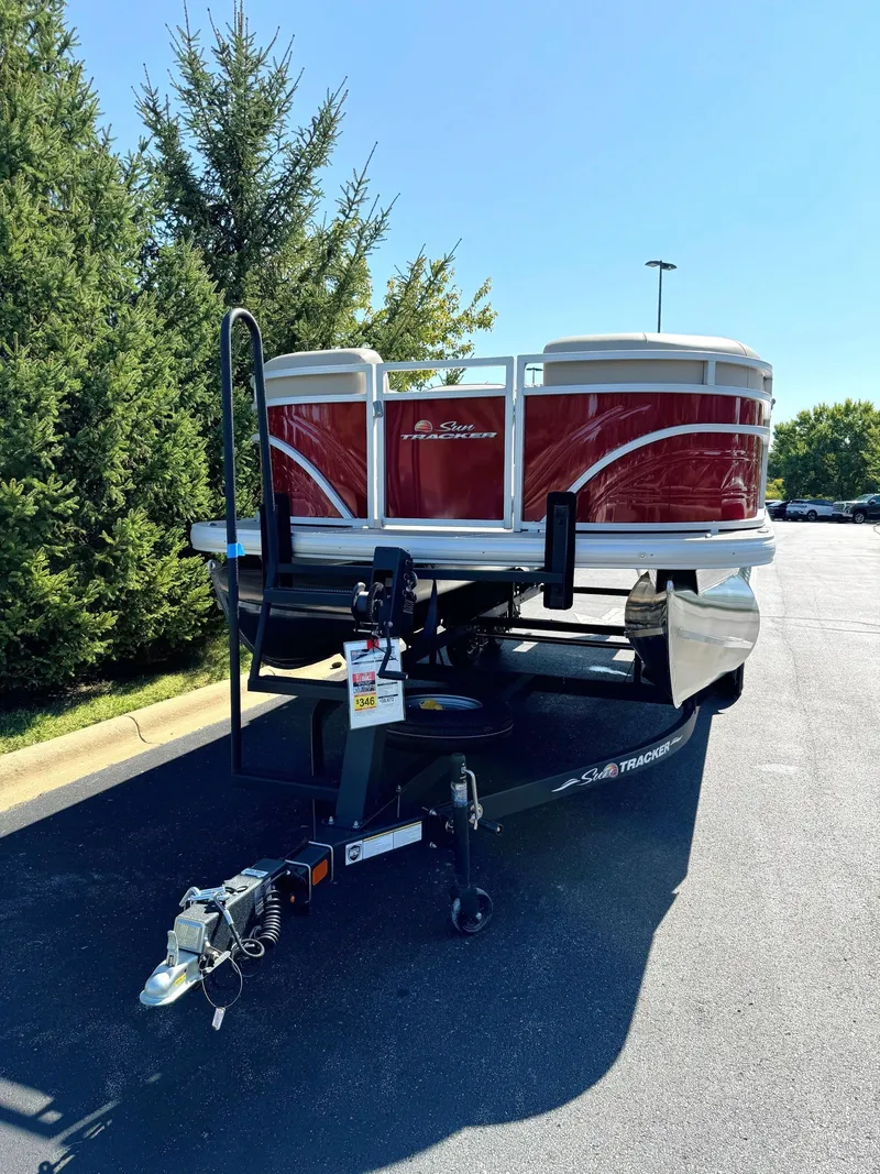 Slide: The Image of 2024 Sun Tracker Party Barge 20 DLX pontoon boat on trailer, parked outdoors. - 2