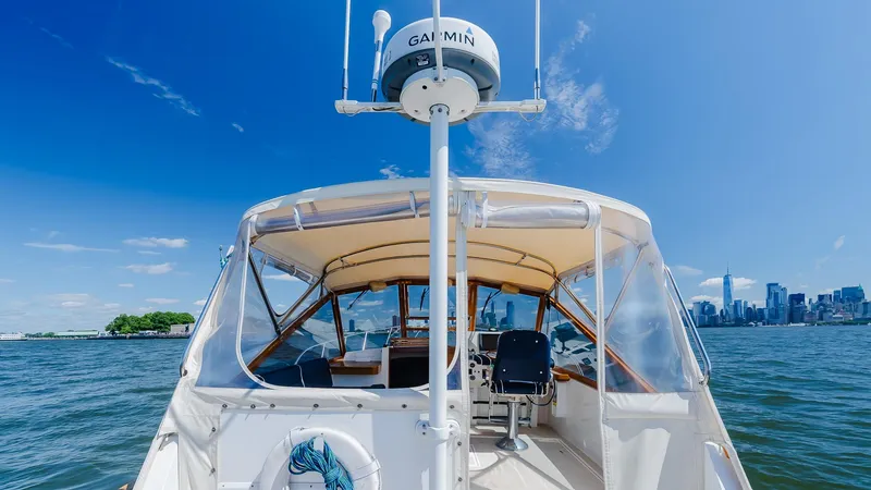 Slide: The Image of Little Harbor WhisperJet 38 boat on water with city skyline in background, clear blue sky. - 13