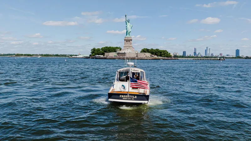 Slide: The Image of Little Harbor WhisperJet 38 boat near Statue of Liberty, 1998 model, with American flag. - 5