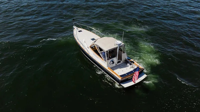 Slide: The Image of 1998 Little Harbor WhisperJet 38 cruising on open water, displaying an American flag. - 9