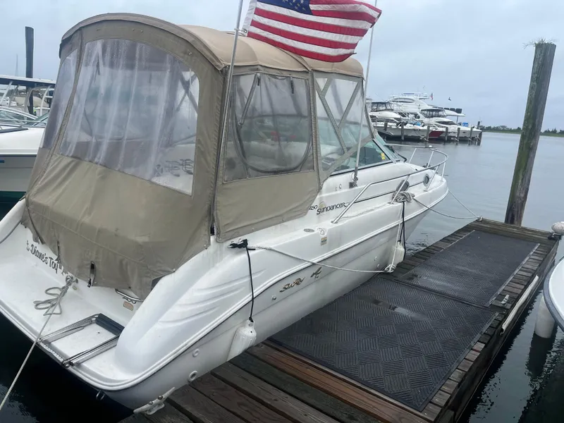Slide: The Image of 1998 Sea Ray 27 Sundancer docked, featuring a beige canopy and American flag. - 21