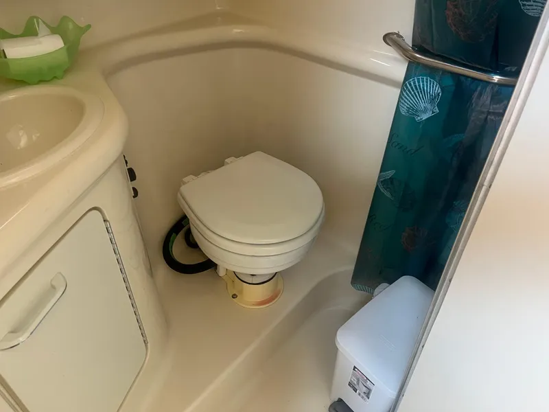 Slide: The Image of 1998 Sea Ray 27 Sundancer bathroom with toilet, sink, and shower curtain. - 7