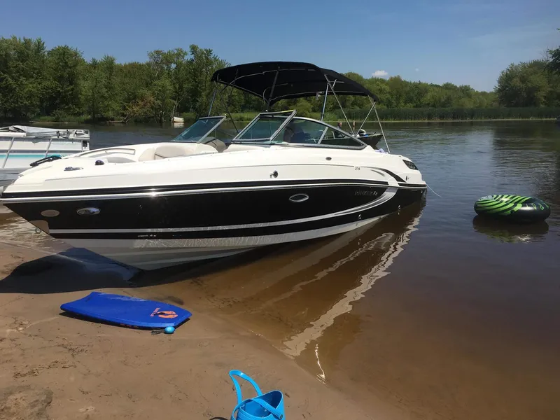 Slide: The Image of 2013 Rinker 276 Captiva Bowrider on sandy shore with water sports gear nearby. - 0
