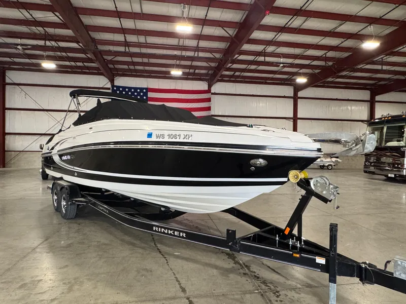 Slide: The Image of 2013 Rinker 276 Captiva Bowrider on trailer in warehouse with American flag. - 11