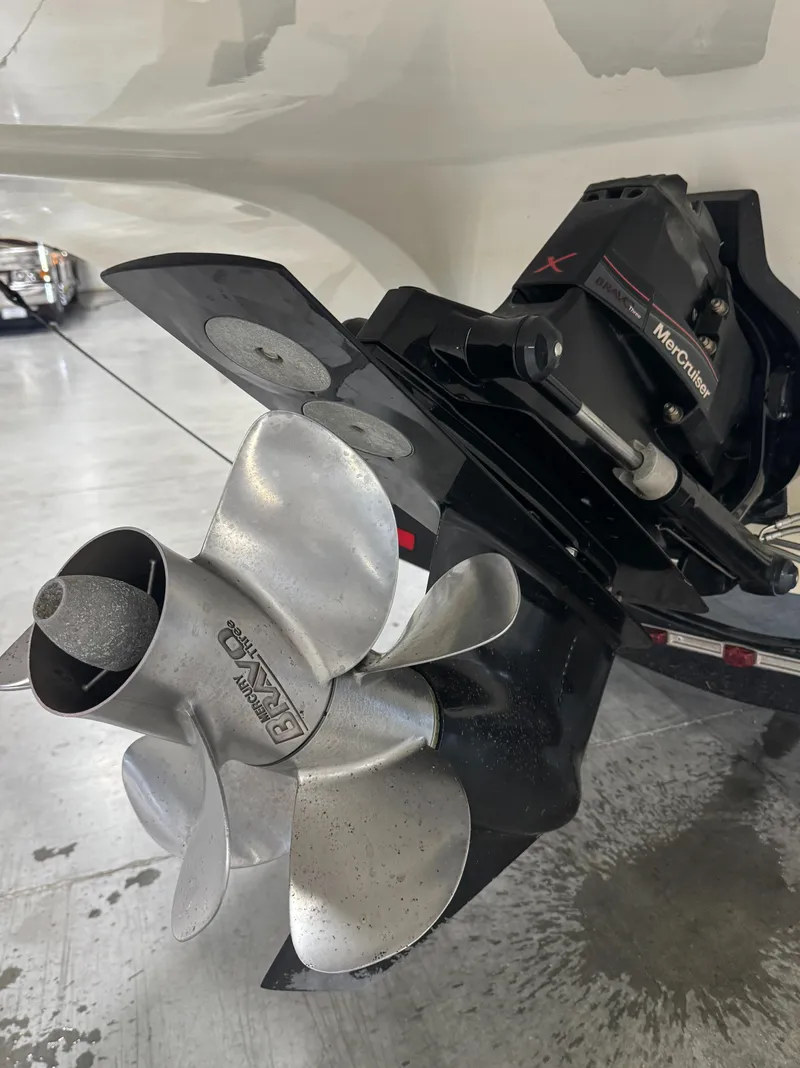 Slide: The Image of 2013 Rinker 276 Captiva Bowrider boat propeller and outdrive in a garage. - 19