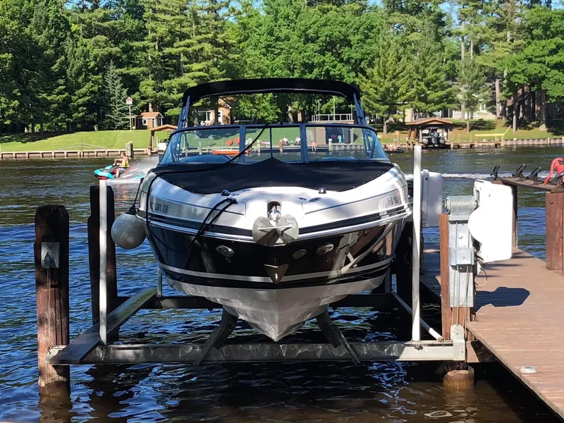 Slide: The Image of 2013 Rinker 276 Captiva Bowrider on a boat lift at a lakeside dock. - 2