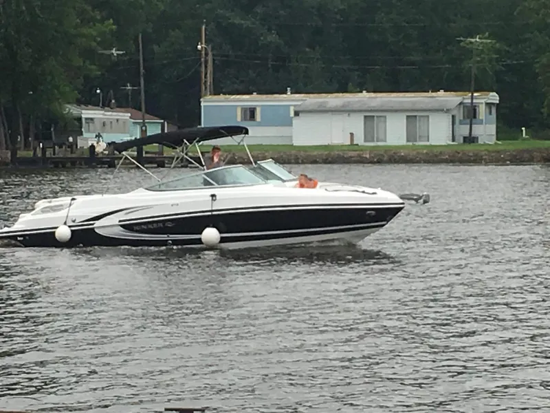 Slide: The Image of 2013 Rinker 276 Captiva Bowrider cruising on a calm lake near shoreline homes. - 3