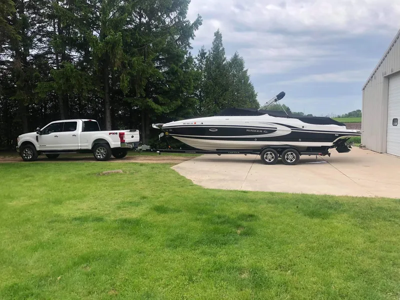 Slide: The Image of White 2013 Rinker 276 Captiva Bowrider on trailer, parked beside a white truck. - 4