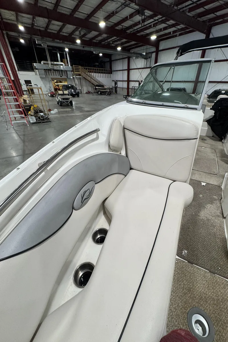 Slide: The Image of 2013 Rinker 276 Captiva Bowrider interior with white seating in a warehouse setting. - 48