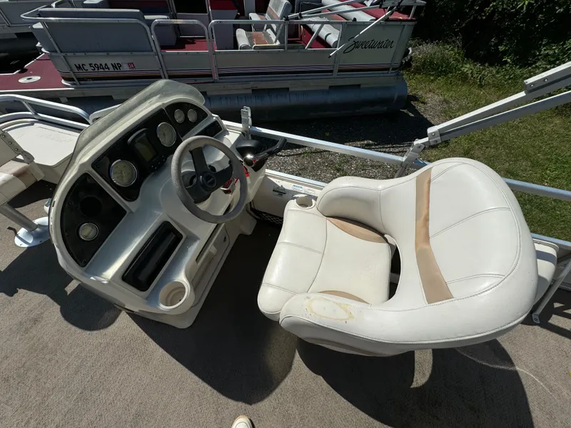 Slide: The Image of Sweetwater 2020DF boat interior, featuring a steering console and cushioned captain's chair, 2005 model. - 5