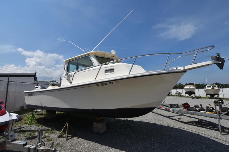Slide: The Image of 2004 Parker 2520 Deep Vee Sport Cabin boat on gravel lot under blue sky. - 0