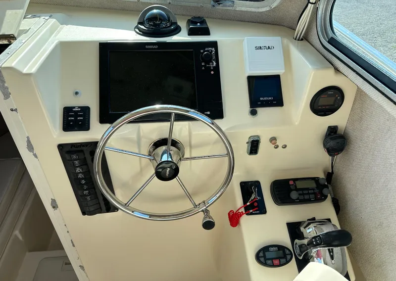 Slide: The Image of 2004 Parker 2520 Deep Vee Sport Cabin helm with steering wheel and navigation controls. - 13