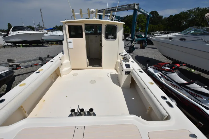 Slide: The Image of 2004 Parker 2520 Deep Vee Sport Cabin boat, spacious deck, marina background. - 6