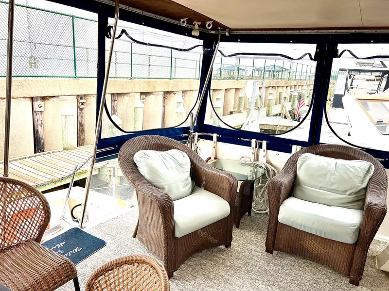 Slide: The Image of 1986 Chris-Craft 480 Corinthian yacht interior with wicker chairs and marina view. - 11