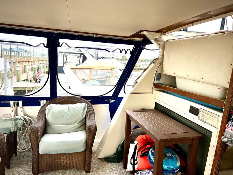 Slide: The Image of 1986 Chris-Craft 480 Corinthian yacht interior with wicker chair and table, dock view. - 12