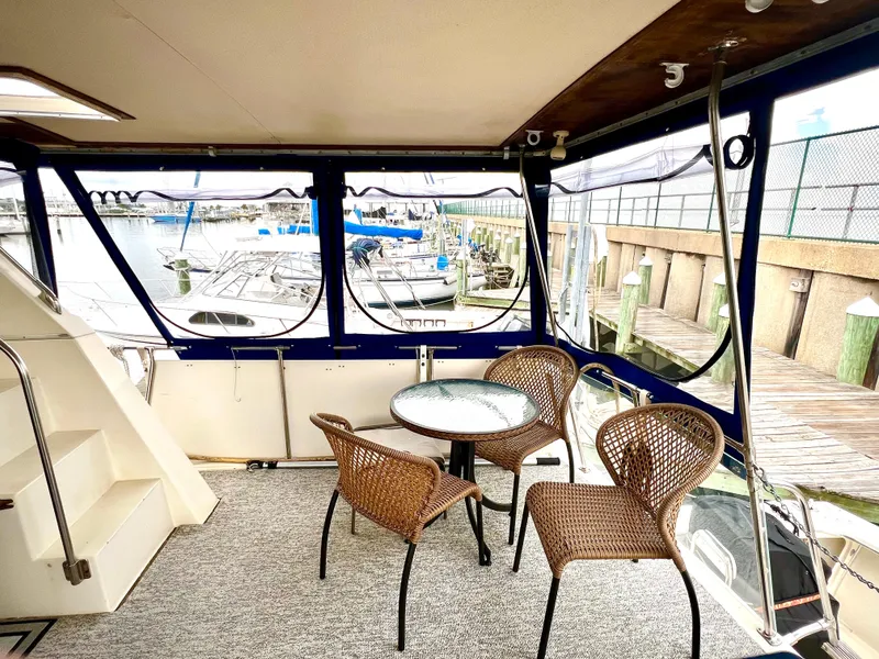 Slide: The Image of 1986 Chris-Craft 480 Corinthian yacht interior with wicker chairs and table, overlooking marina. - 16