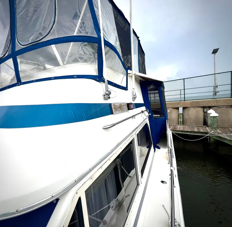 Slide: The Image of 1986 Chris-Craft 480 Corinthian yacht docked, featuring blue and white exterior. - 25