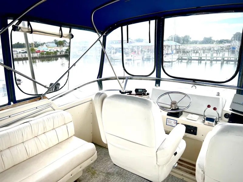 Slide: The Image of Interior of 1986 Chris-Craft 480 Corinthian yacht with white seating and marina view. - 30