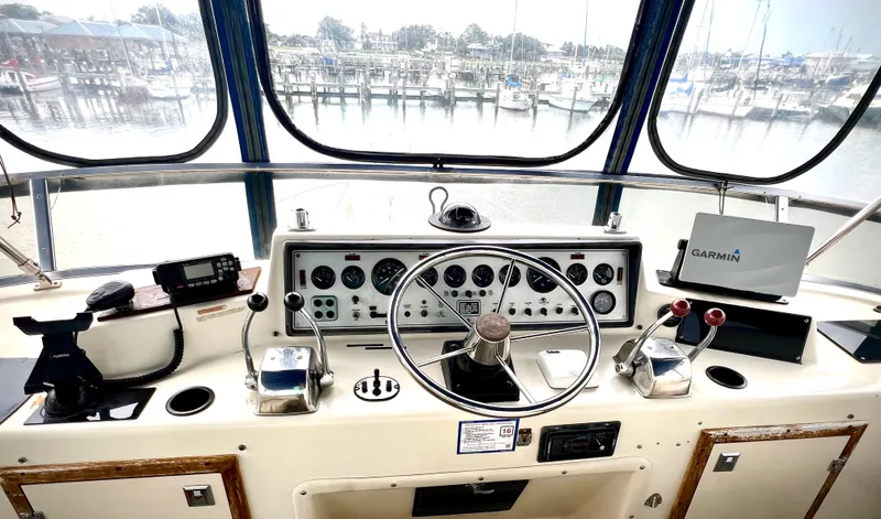Slide: The Image of Helm of 1986 Chris-Craft 480 Corinthian yacht with navigation equipment and marina view. - 32