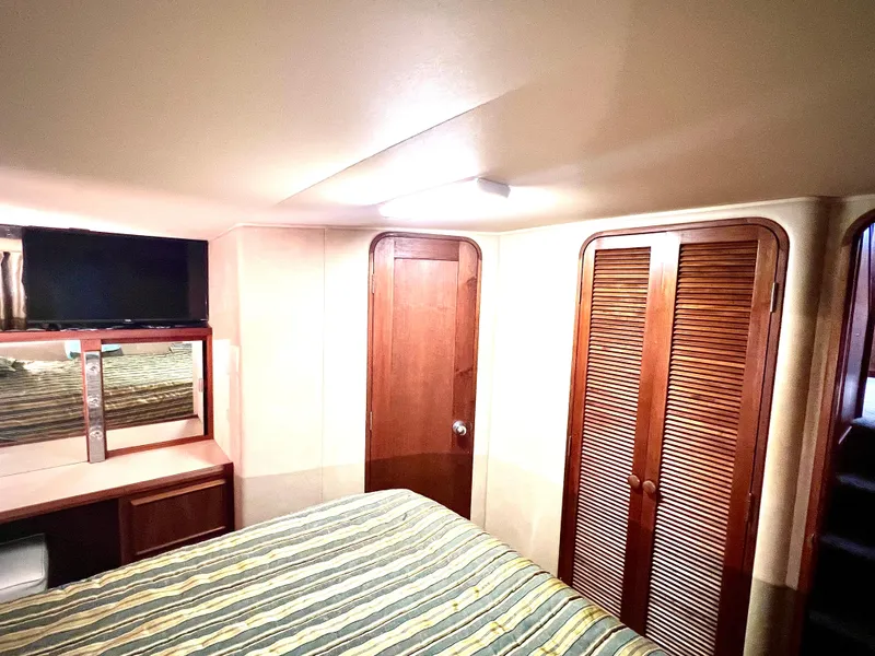 Slide: The Image of Interior cabin of 1986 Chris-Craft 480 Corinthian with bed, TV, and wooden closets. - 49