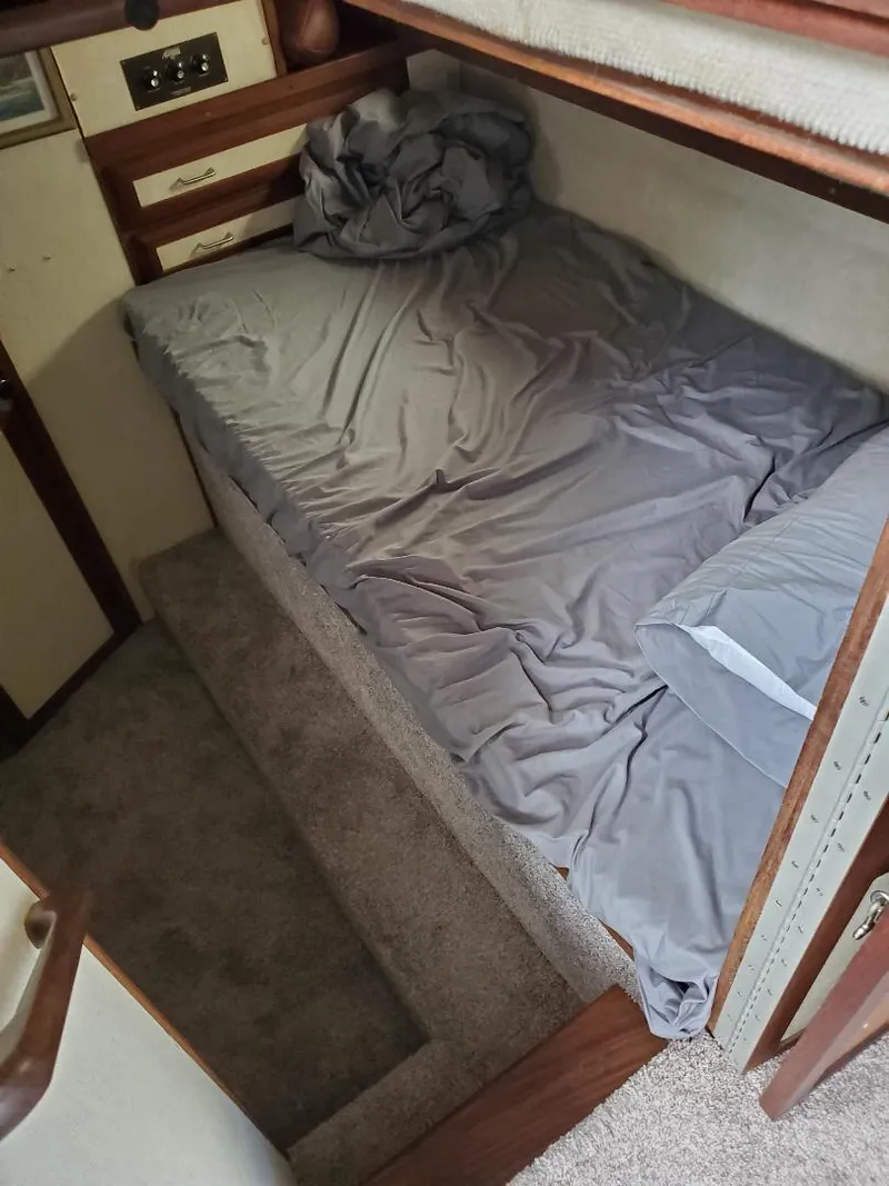 Slide: The Image of 1983 Carver 3207 AFT Cabin Motor Yacht interior with a cozy bed and gray bedding. - 5