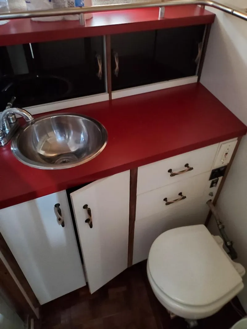 Slide: The Image of 1983 Carver 3207 AFT Cabin Motor Yacht bathroom with red countertop and stainless steel sink. - 7