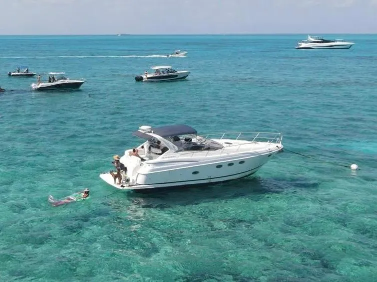 Slide: The Image of 2003 Regal Commodore 3860 yacht anchored in clear turquoise waters, surrounded by smaller boats. - 0
