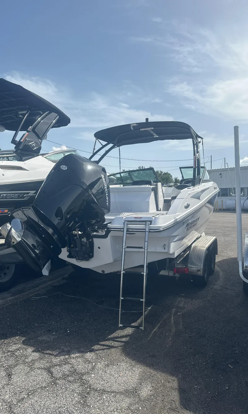 Slide: The Image of 2025 Monterey M-225 boat with outboard motor, parked on a trailer under a cloudy sky. - 7