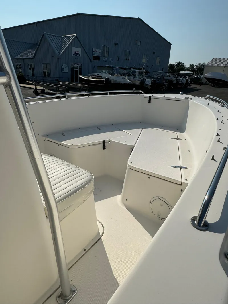 Slide: The Image of 2005 Sea Hunt Triton 232 boat interior with seating, docked near a warehouse. - 11