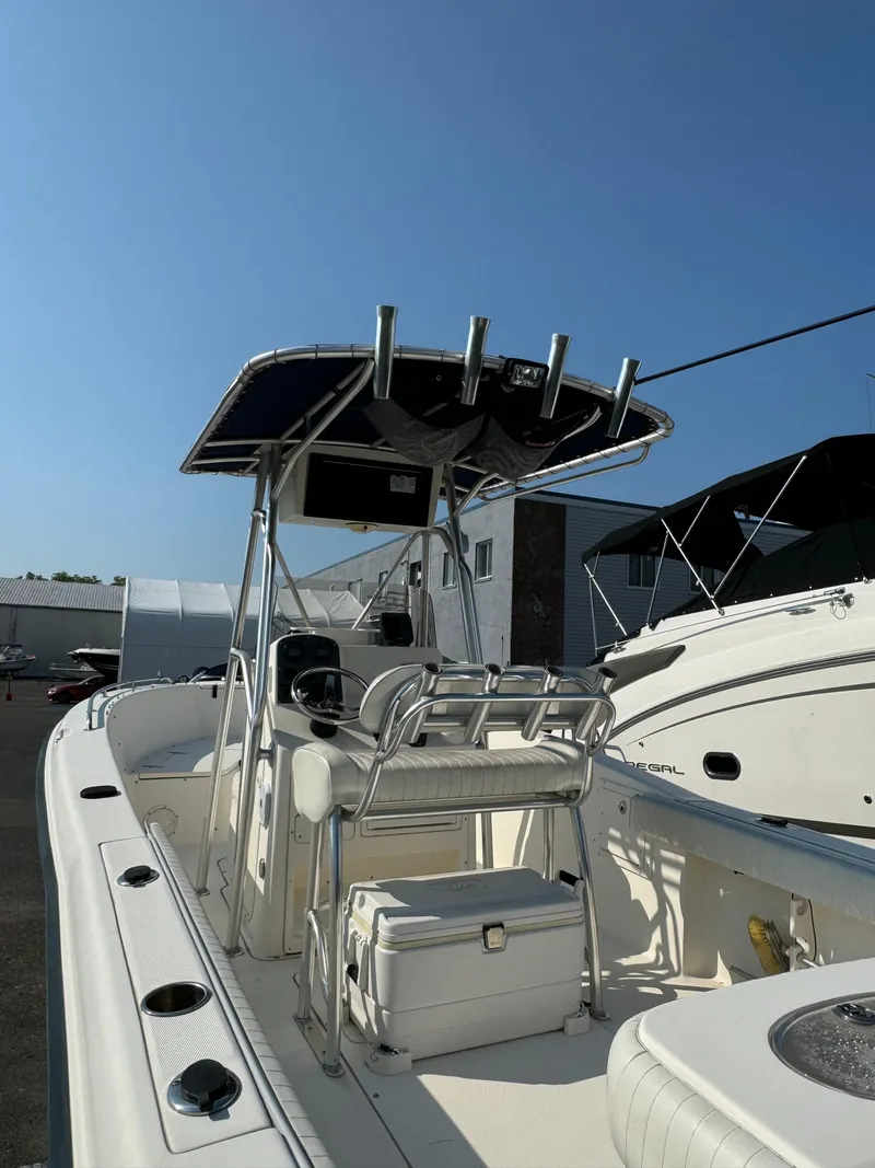 Slide: The Image of 2005 Sea Hunt Triton 232 boat with T-top and seating, docked under clear sky. - 5
