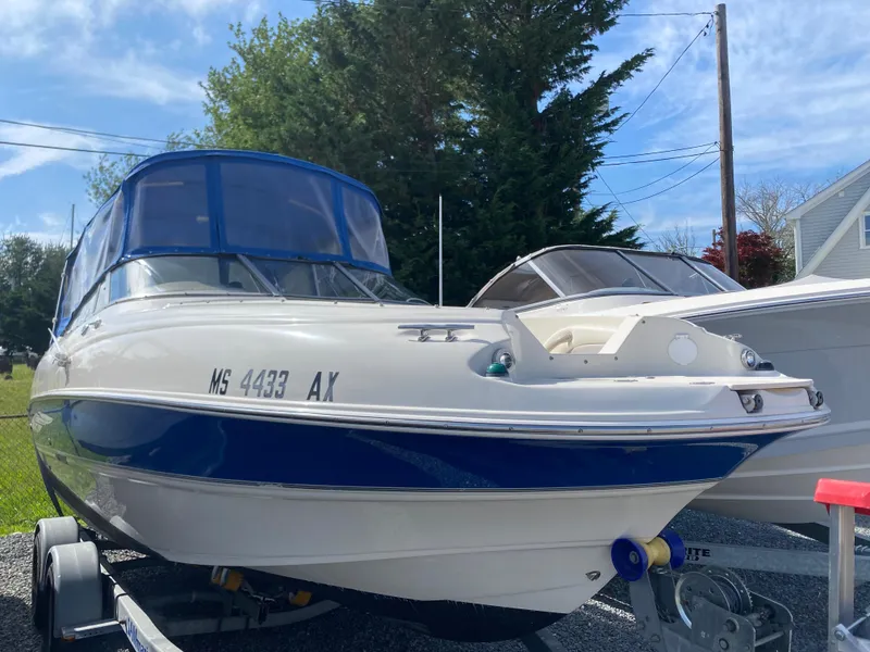 Slide: The Image of 2007 Stingray 22 DR boat with blue canopy on trailer, parked outdoors. - 4