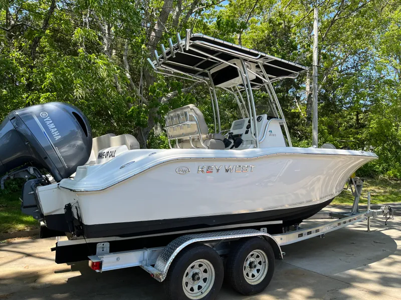 Slide: The Image of 2021 Key West 219 FS boat on trailer, featuring Yamaha engine, surrounded by trees. - 7