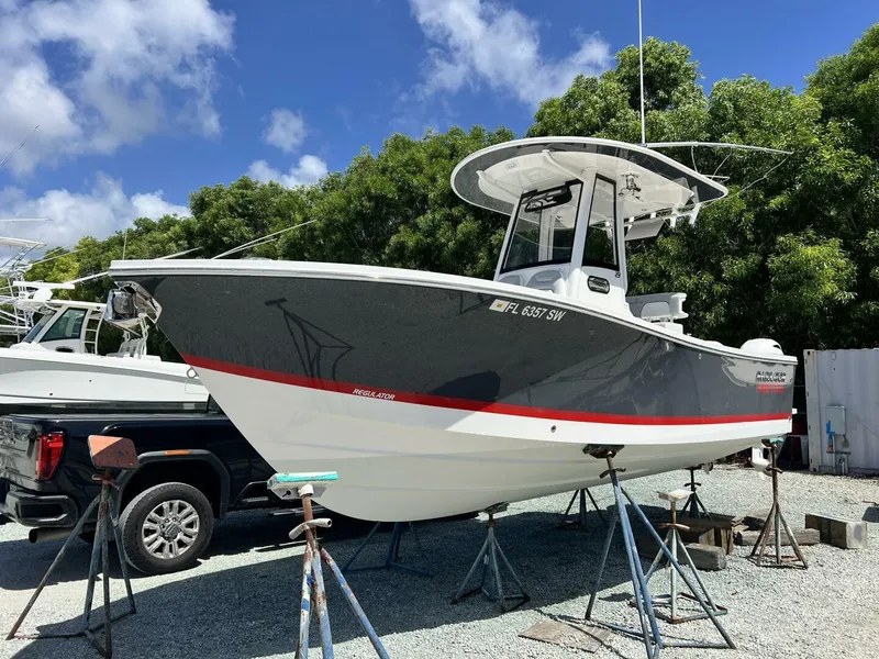 Slide: The Image of 2020 Regulator 23 boat on stands, gray and white hull, sunny day. - 10