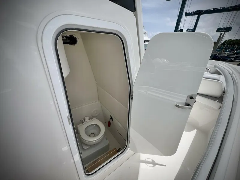Slide: The Image of 2020 Regulator 23 boat interior with open door revealing compact marine toilet. - 26