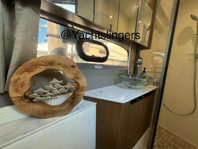 Slide: The Image of 2017 Sea Ray Sundancer bathroom with modern sink, decorative wood art, and glass shower. - 15