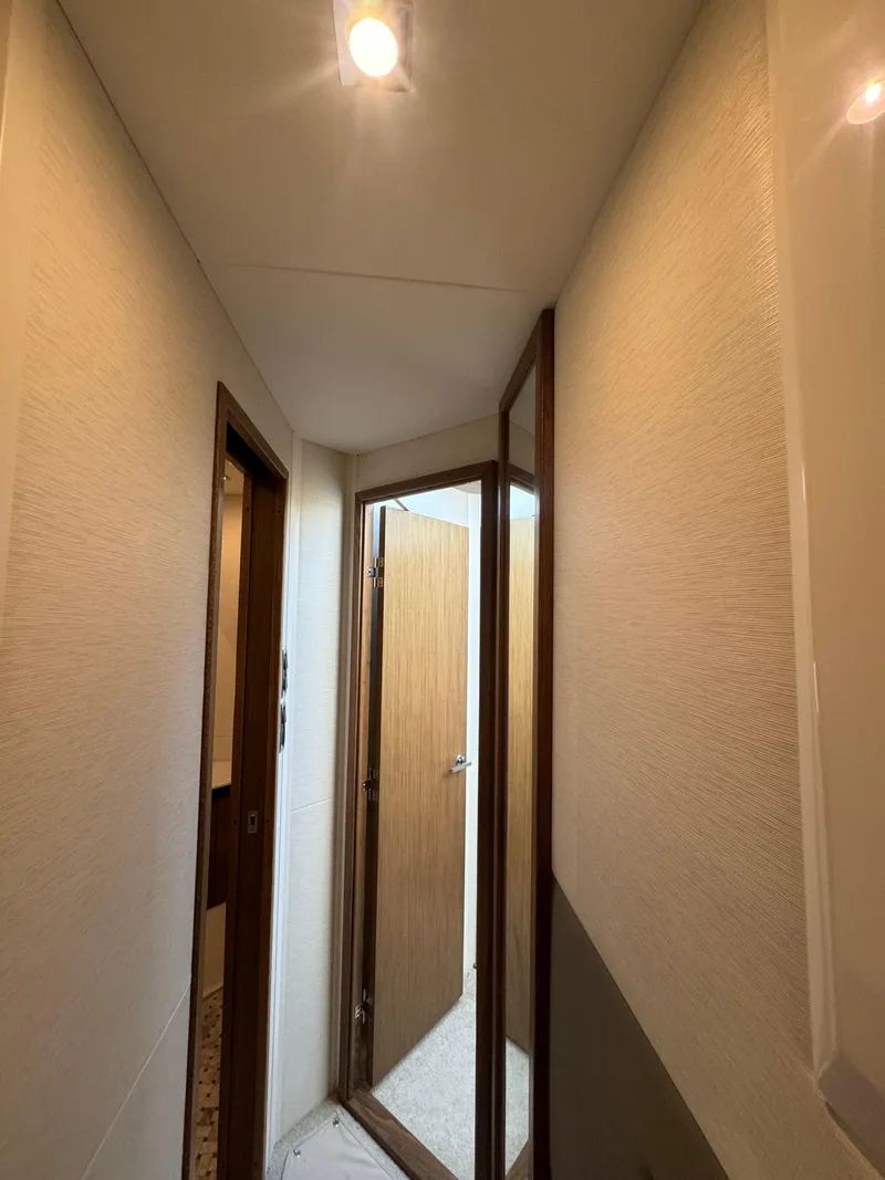Slide: The Image of Narrow hallway inside 2017 Sea Ray Sundancer yacht with wooden doors and soft lighting. - 23