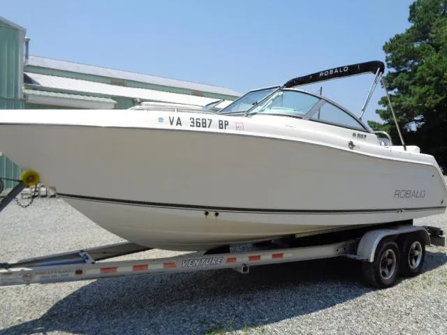 Slide: The Image of 2009 Robalo R227 Dual Console boat on a trailer in a yard. - 13