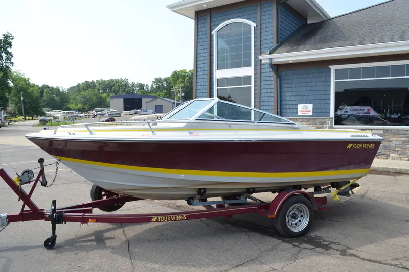 The Image of 1986 Four Winns Open Bow boat on trailer, parked outside a building. - 0
