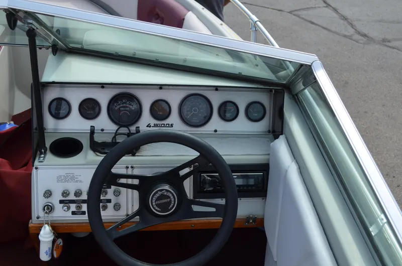 Slide: The Image of 1986 Four Winns Open Bow boat dashboard with steering wheel and gauges. - 2