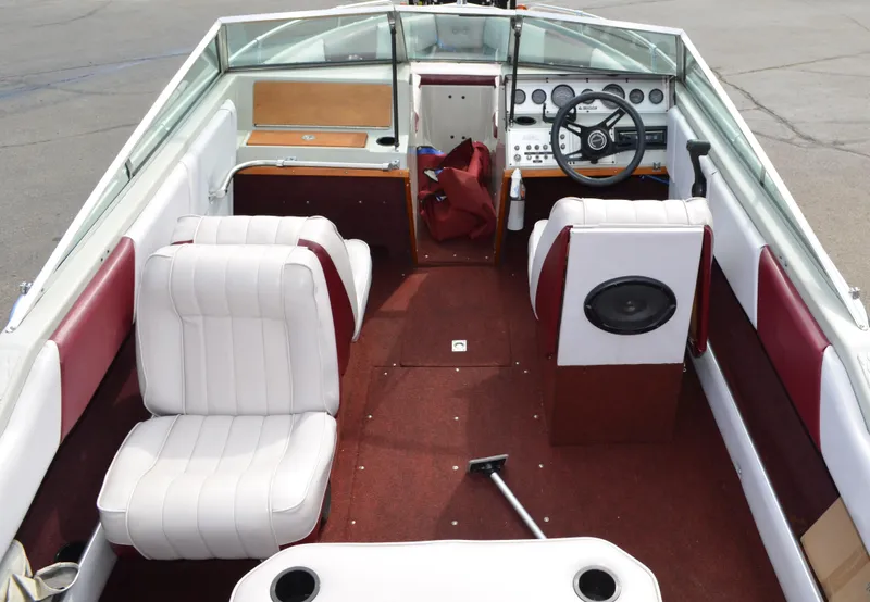 Slide: The Image of 1986 Four Winns Open Bow boat interior with white and red seating, steering wheel, and dashboard. - 9