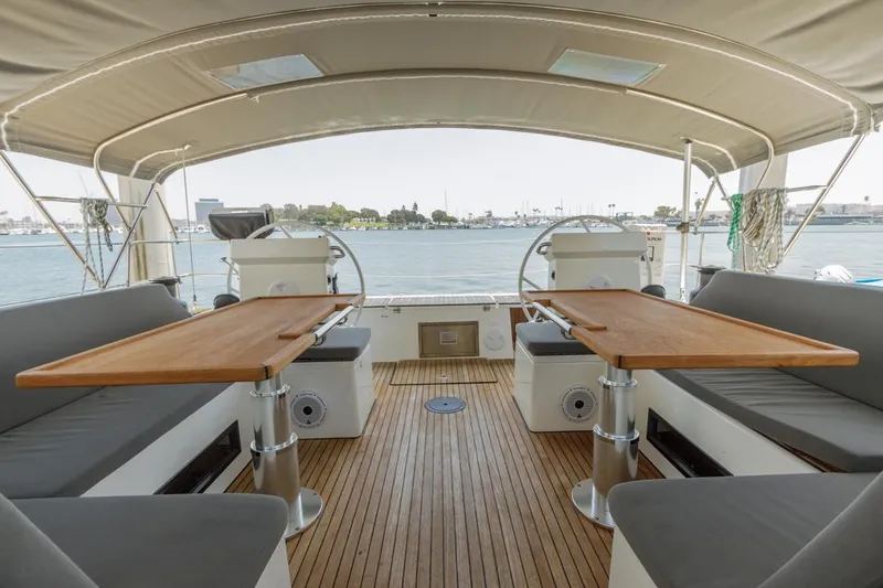 Slide: The Image of Spacious deck of 2022 Bavaria C50 yacht with dual steering wheels and wooden tables. - 16