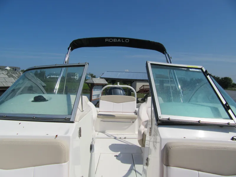 Slide: The Image of 2019 Robalo R207 Dual Console boat with open windshield, docked under clear blue sky. - 11