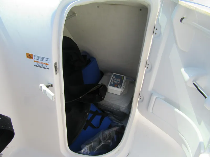 Slide: The Image of Storage compartment in 2019 Robalo R207 Dual Console boat, containing life jackets and equipment. - 6