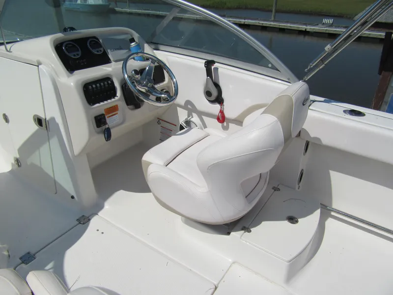 Slide: The Image of 2019 Robalo R207 Dual Console boat interior with steering wheel and white seating. - 9