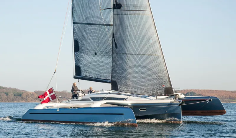 Slide: The Image of Sleek 2026 Dragonfly 32 trimaran sailing on calm waters with Danish flag. - 1