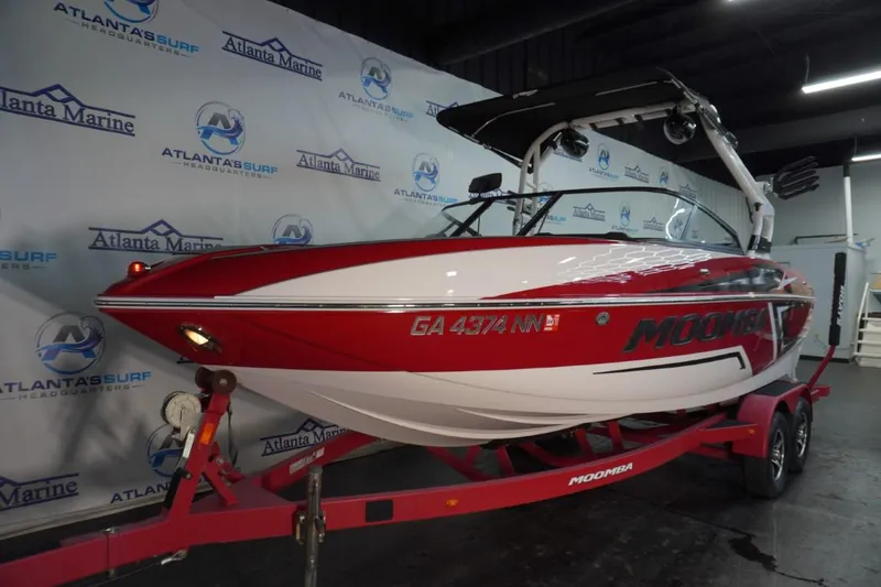 Slide: The Image of 2019 Moomba Craz (MG) boat in showroom, red and white design, on trailer. - 2
